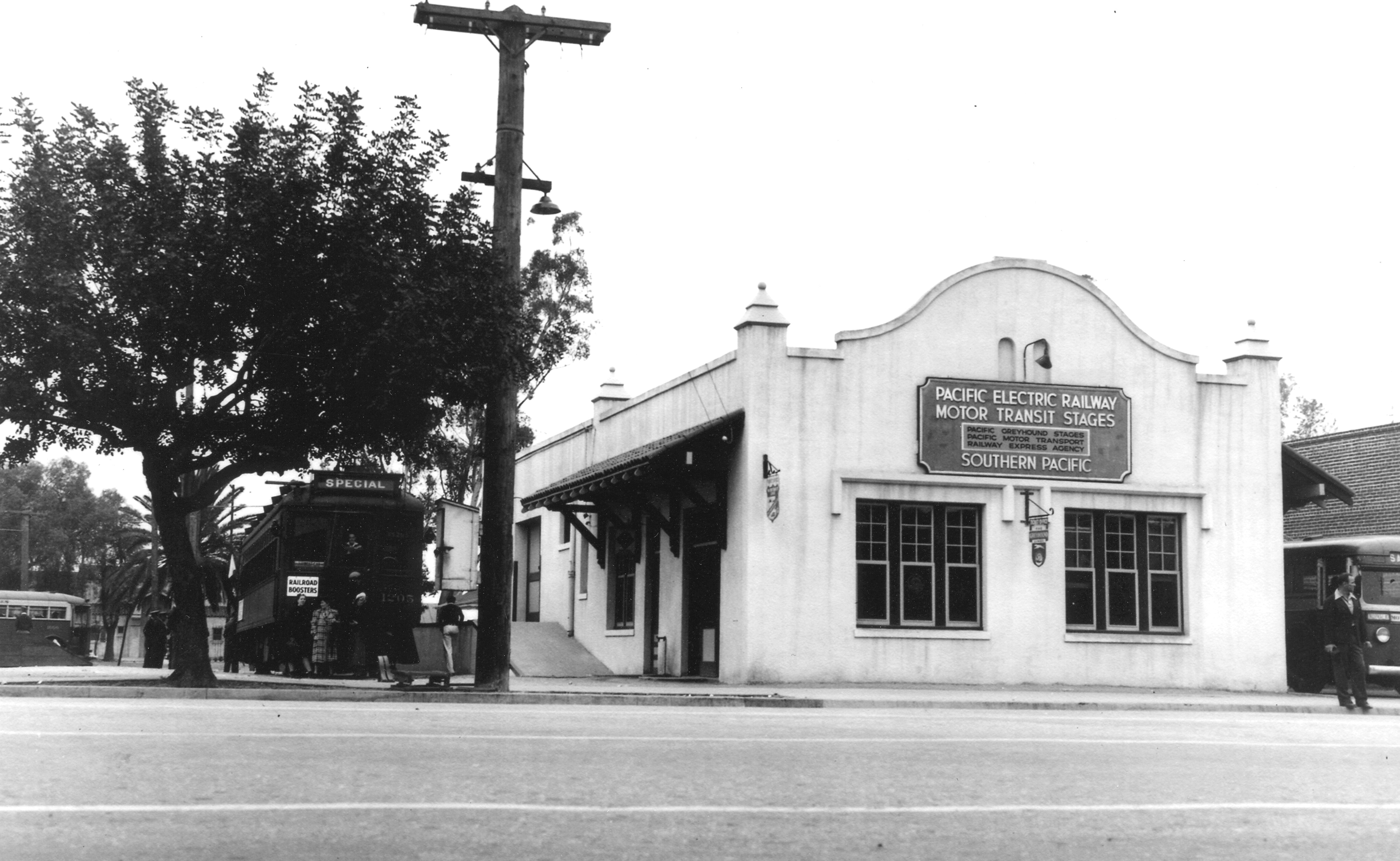 A black and white photograph of the Pacific Electric Depot with waiting Pacific Electric car and bus.