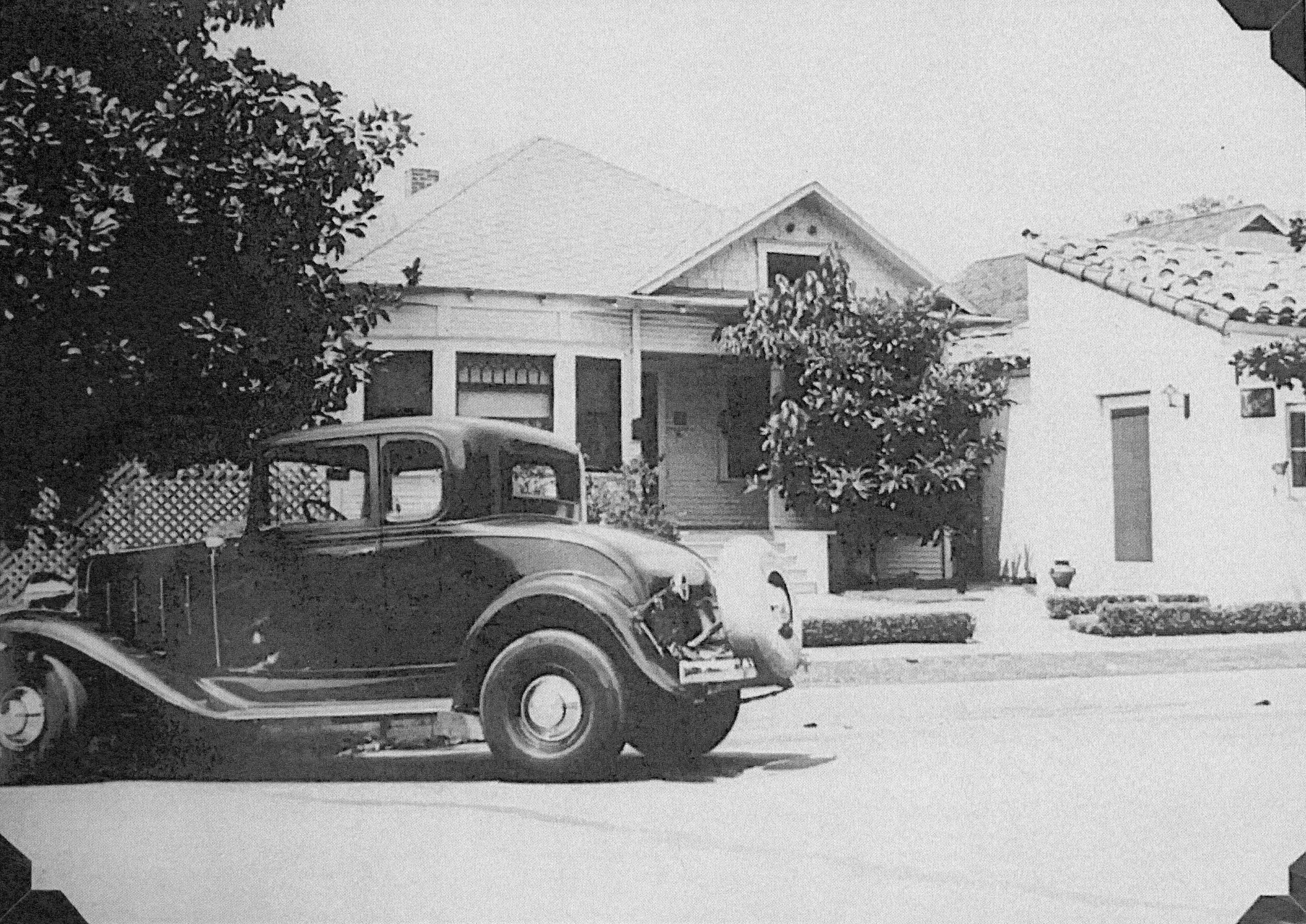 A black and white photograph of the home (Dr. Olson Home &amp; Medical Office) with a car for house calls.