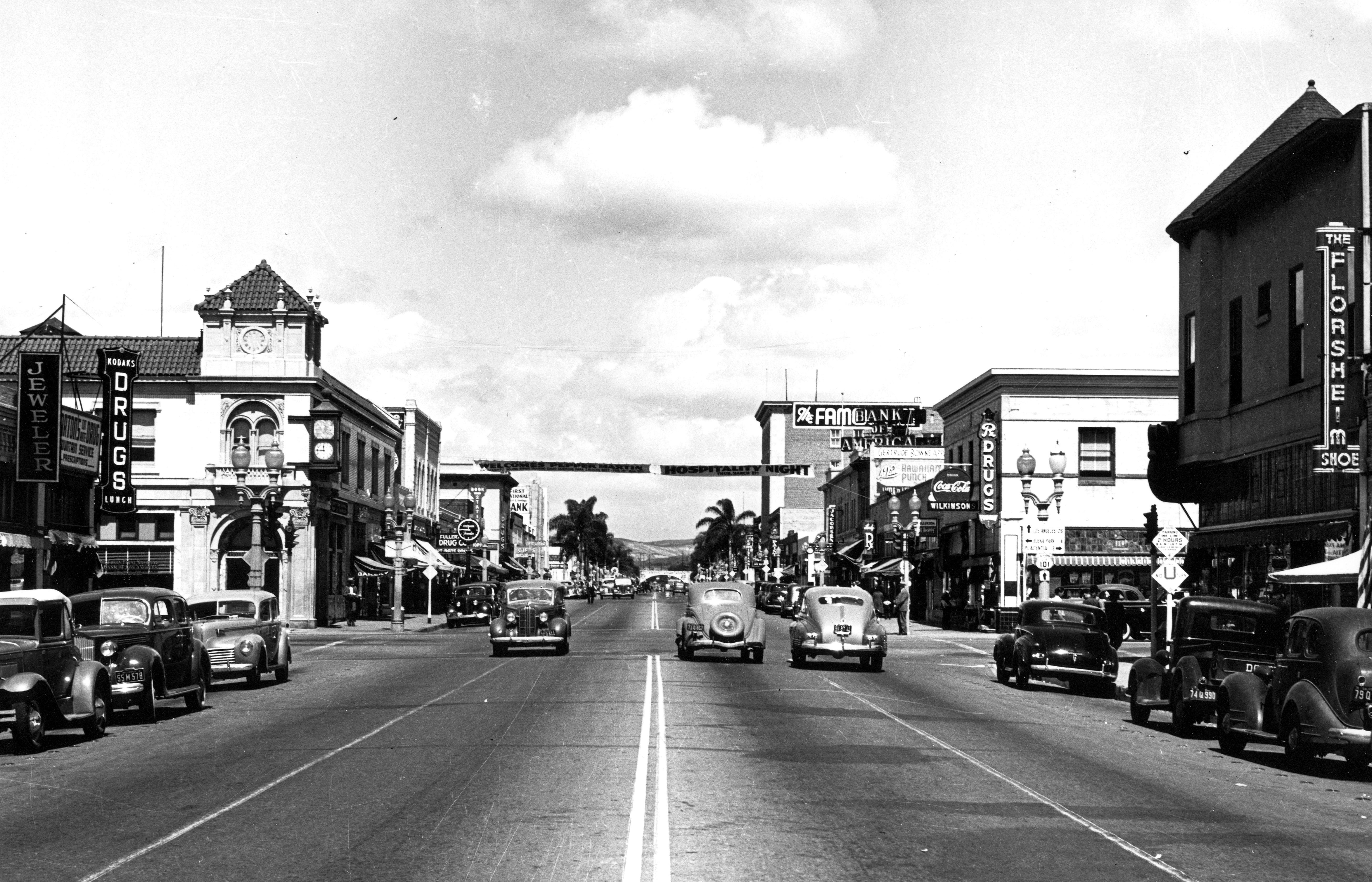 A black and white photograph of the street scene with the Stedman Jewelers&#039; Clock on the west side in 1945.