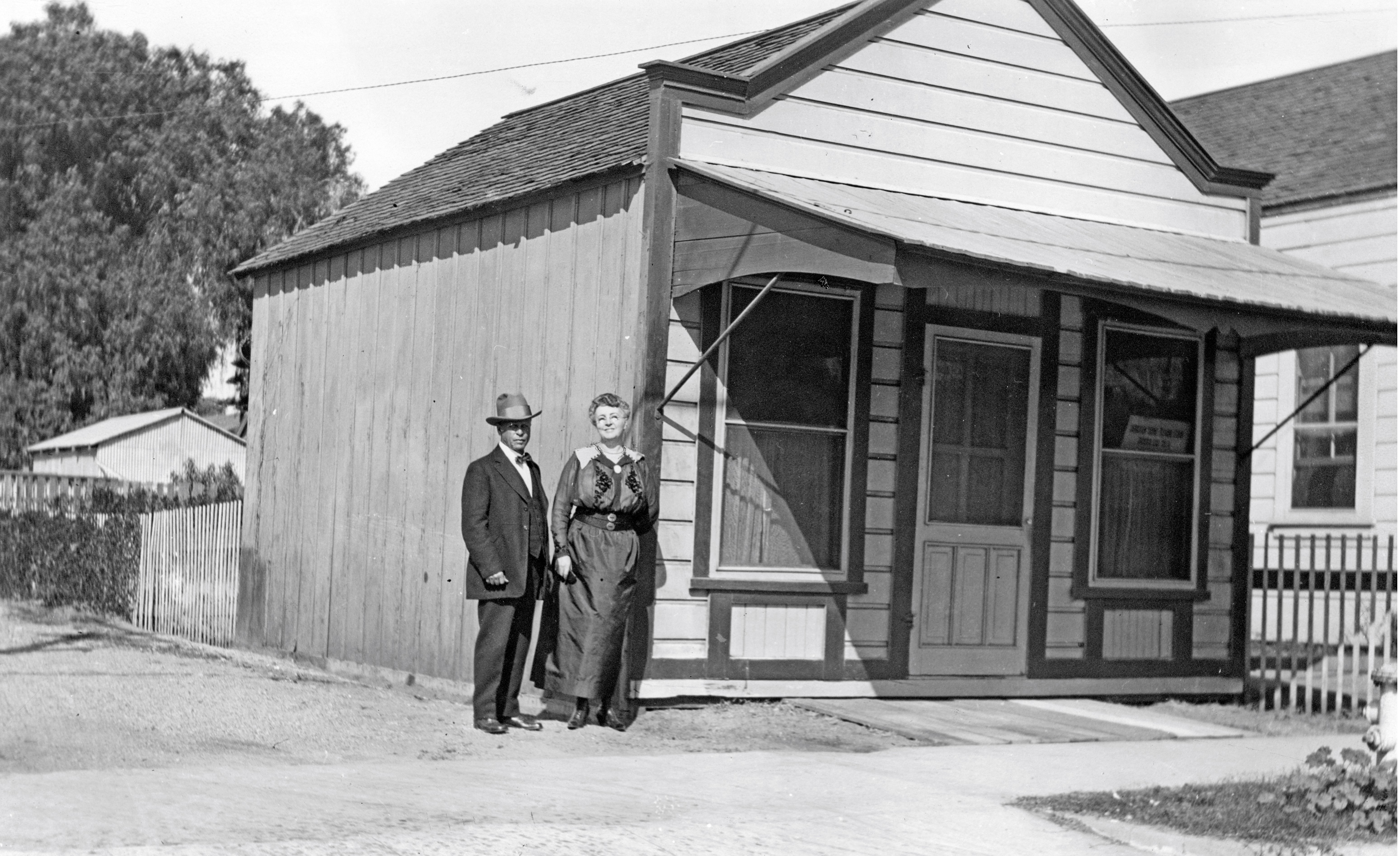 A black and white photograph of George and Annette Amerige standing in front of the real estate office on South Harbor.