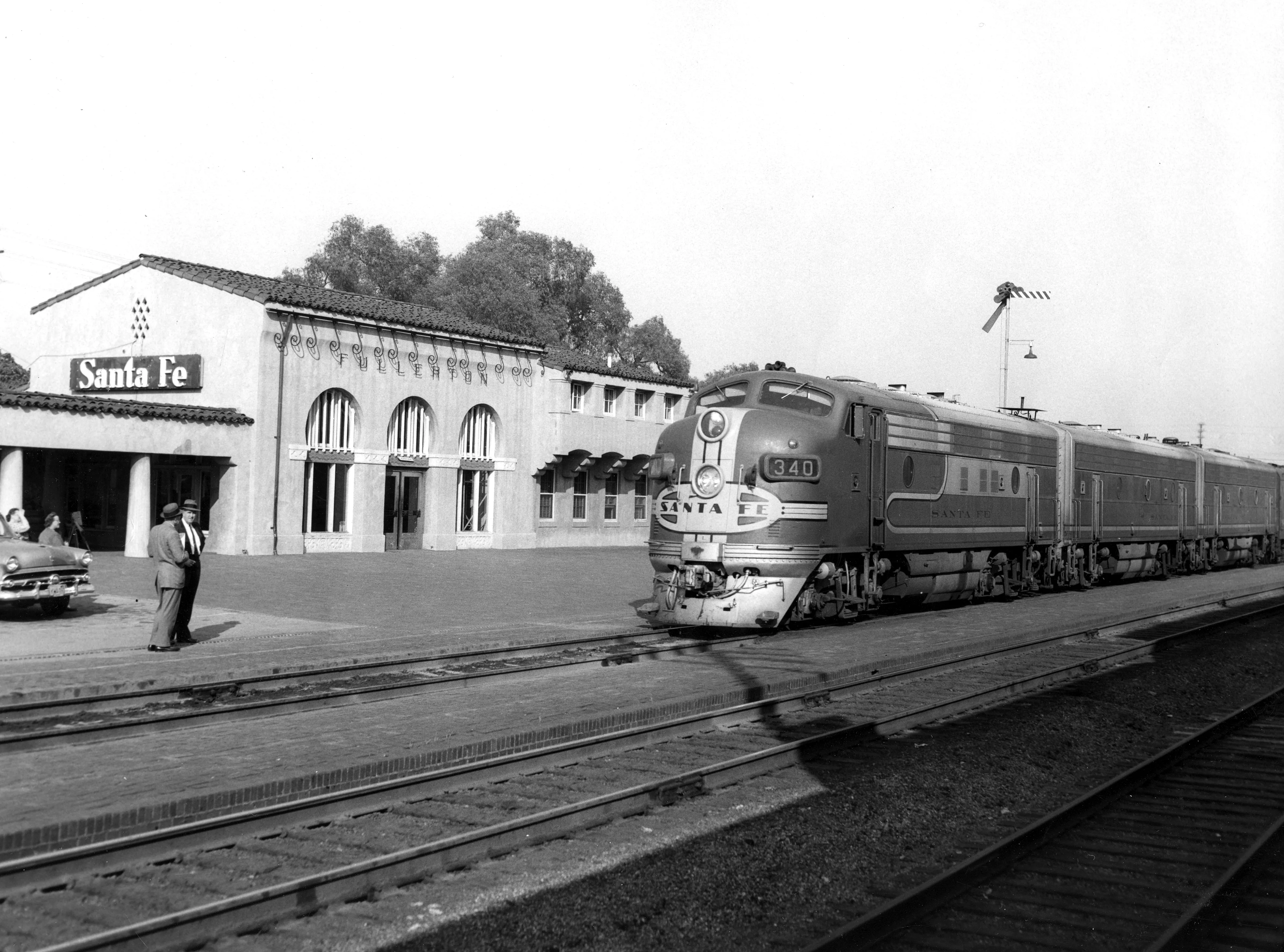 A black and white photograph of the exterior of the Santa Fe Railway Passenger &amp; Freight Depot in 1955.