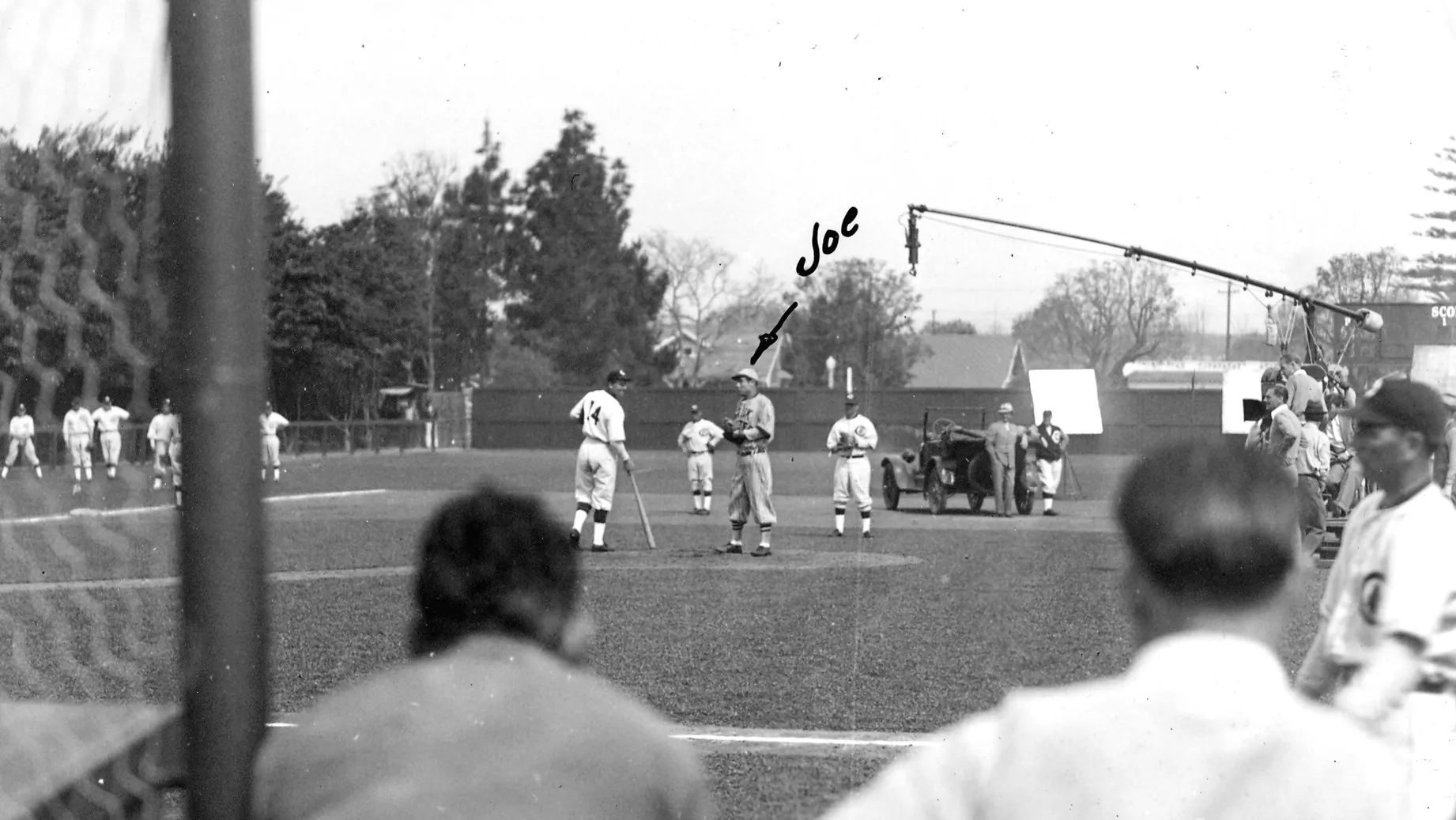 A black and white photograph of the filming of Alibi Ike in 1935 at Amerige Park. "Joe" is written in the middle of the photo, with an arrow pointing at the center right player standing in the photo.
