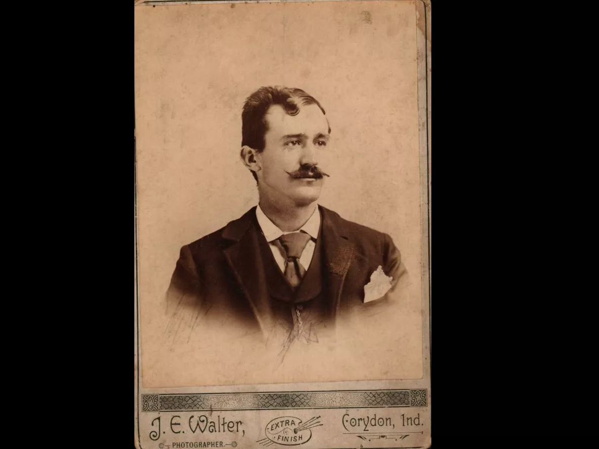 A vintage portrait photograph of James Glenn. The bottom of the photo contains a logo of Extra Finish and reads: J.E. Walter, Photographer. Corydon, Ind.