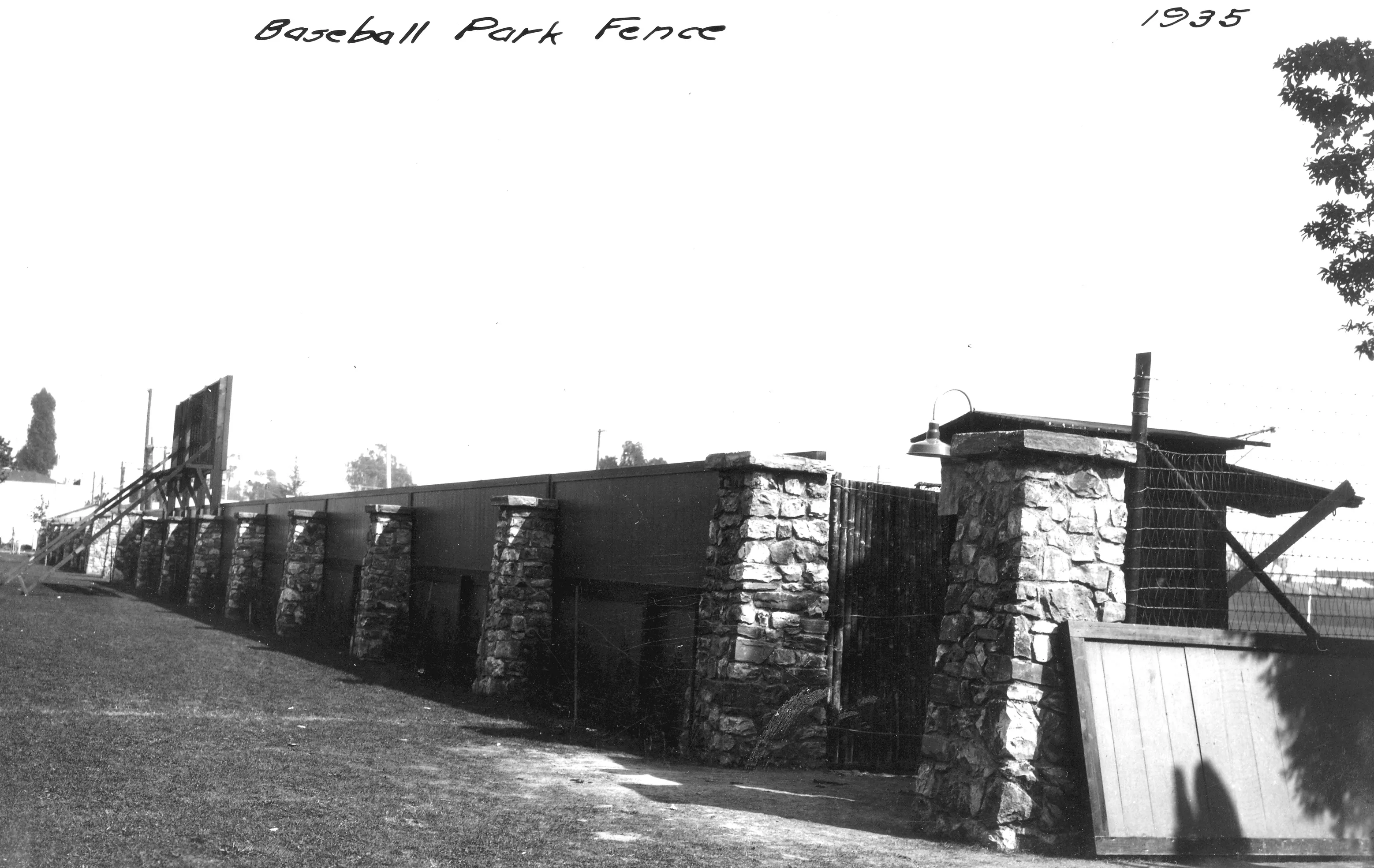 A black and white photograph of the stone pilasters with a fence at Amerige Park in 1935. The handwriting above the picture reads: Baseball Park Fence 1935.