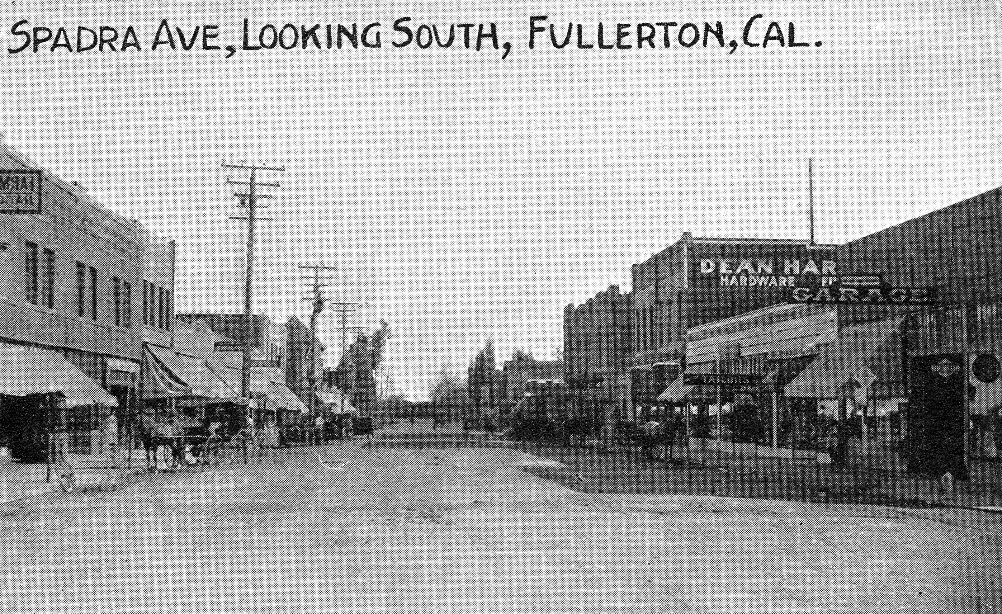 A black and white photograph of the street scene of the Dean Block circa 1913. The top of the photo reads: Spadra Avenue, Looking South, Fullerton, California.