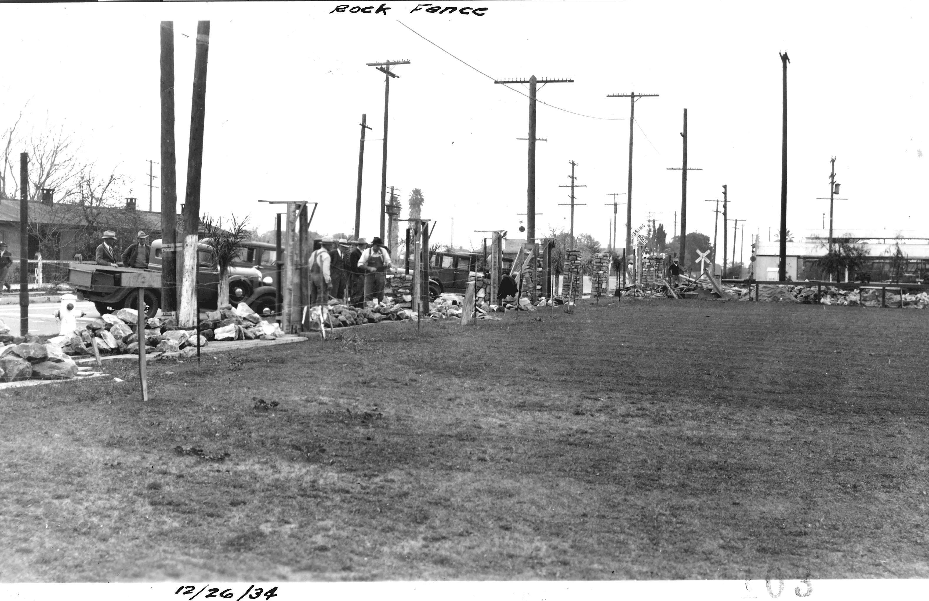 A black and white photograph of the stone pilasters under construction at Amerige Park in 1934. The handwriting at the top of the picture reads: Rock Fence, while the handwriting below the picture reads: December 26, 1934.