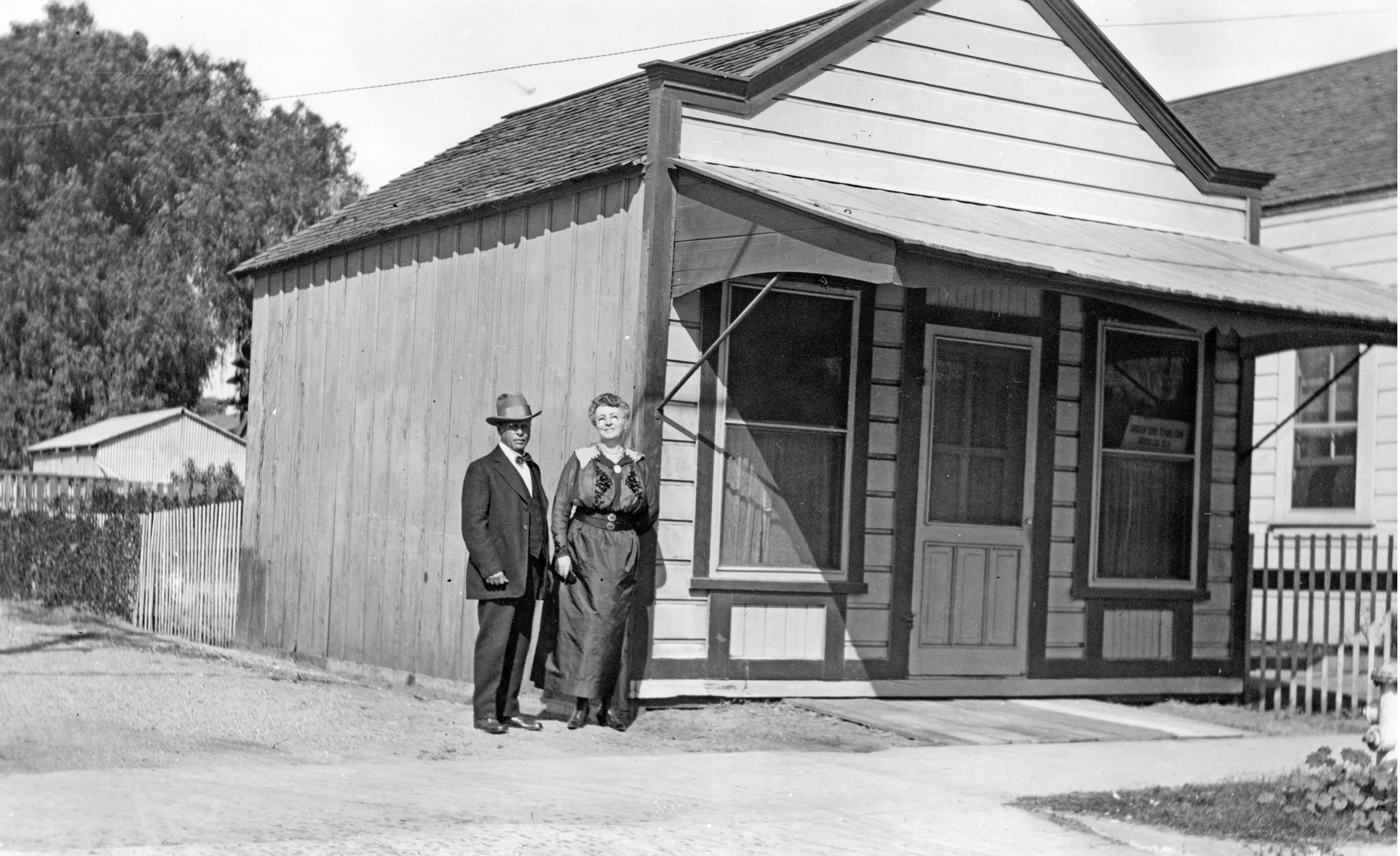 A black and white photograph of George and Annette Amerige standing in front of the real estate office on South Harbor.