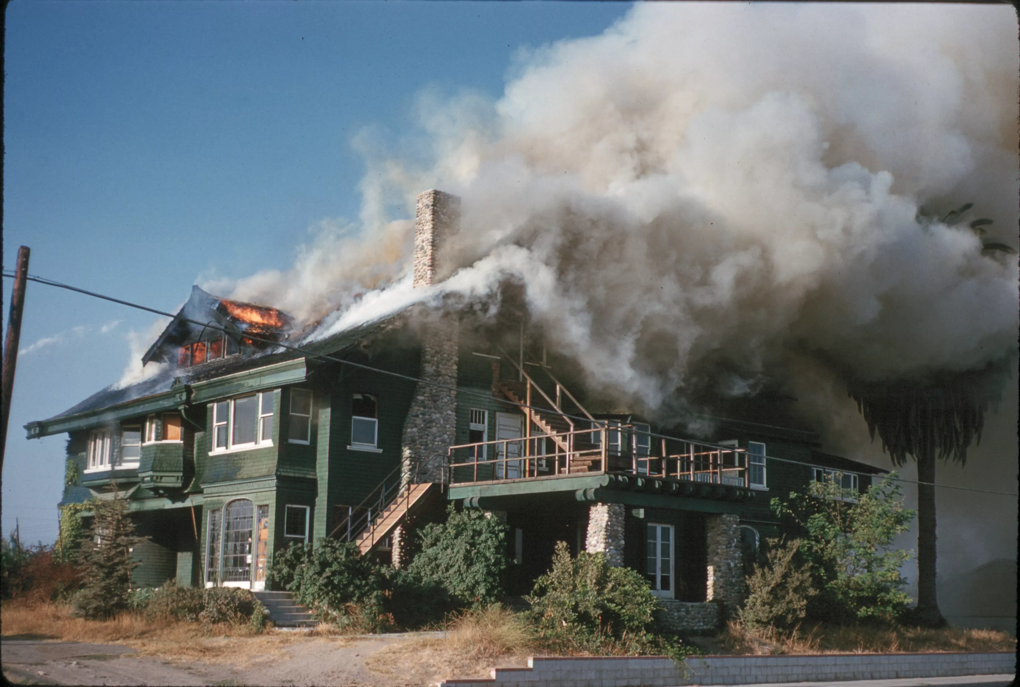 A colored photo of the Chapman House on fire and burning in 1960.