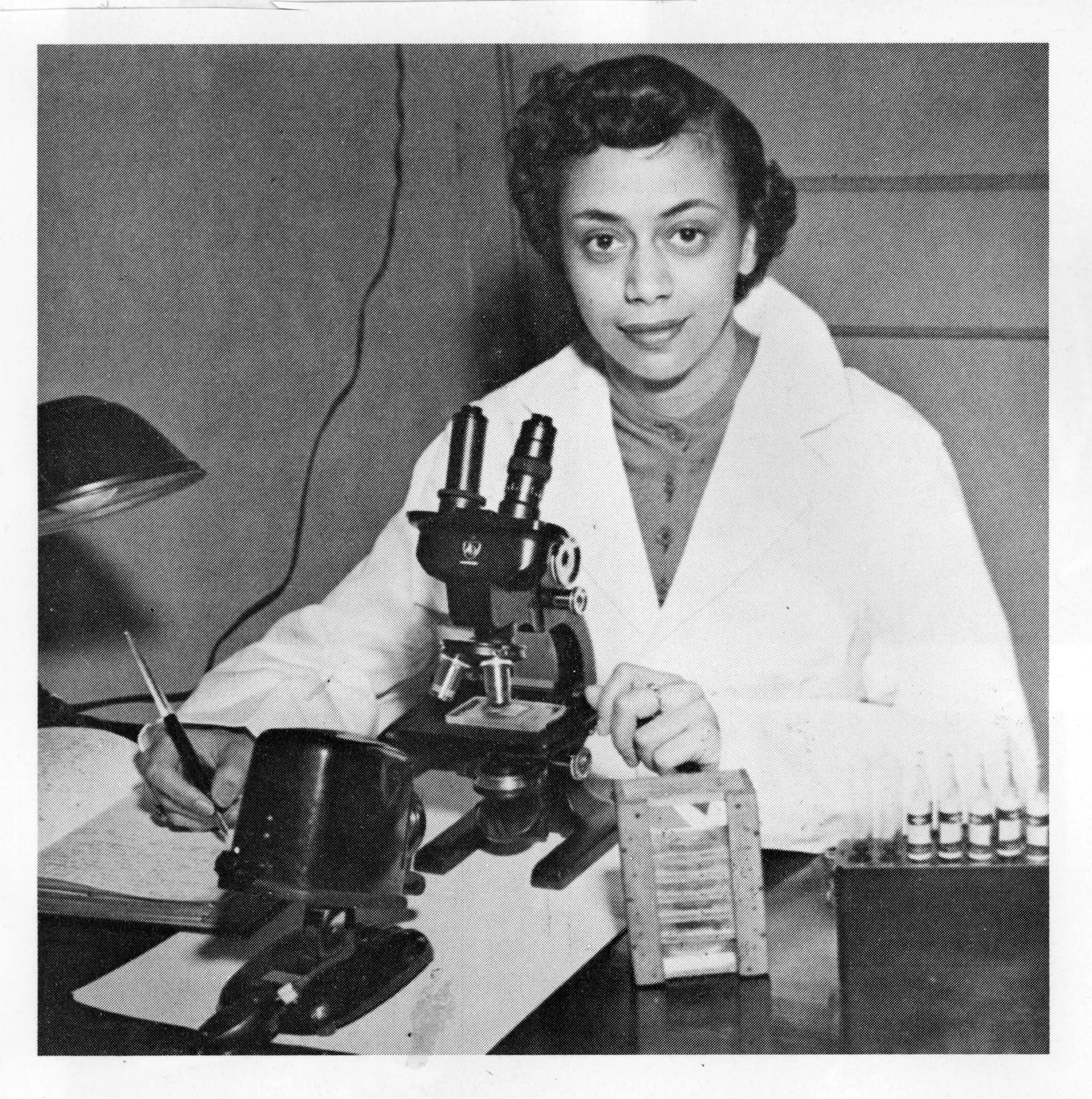 An image of Jewell Plummer Cobb sitting at a microscope.