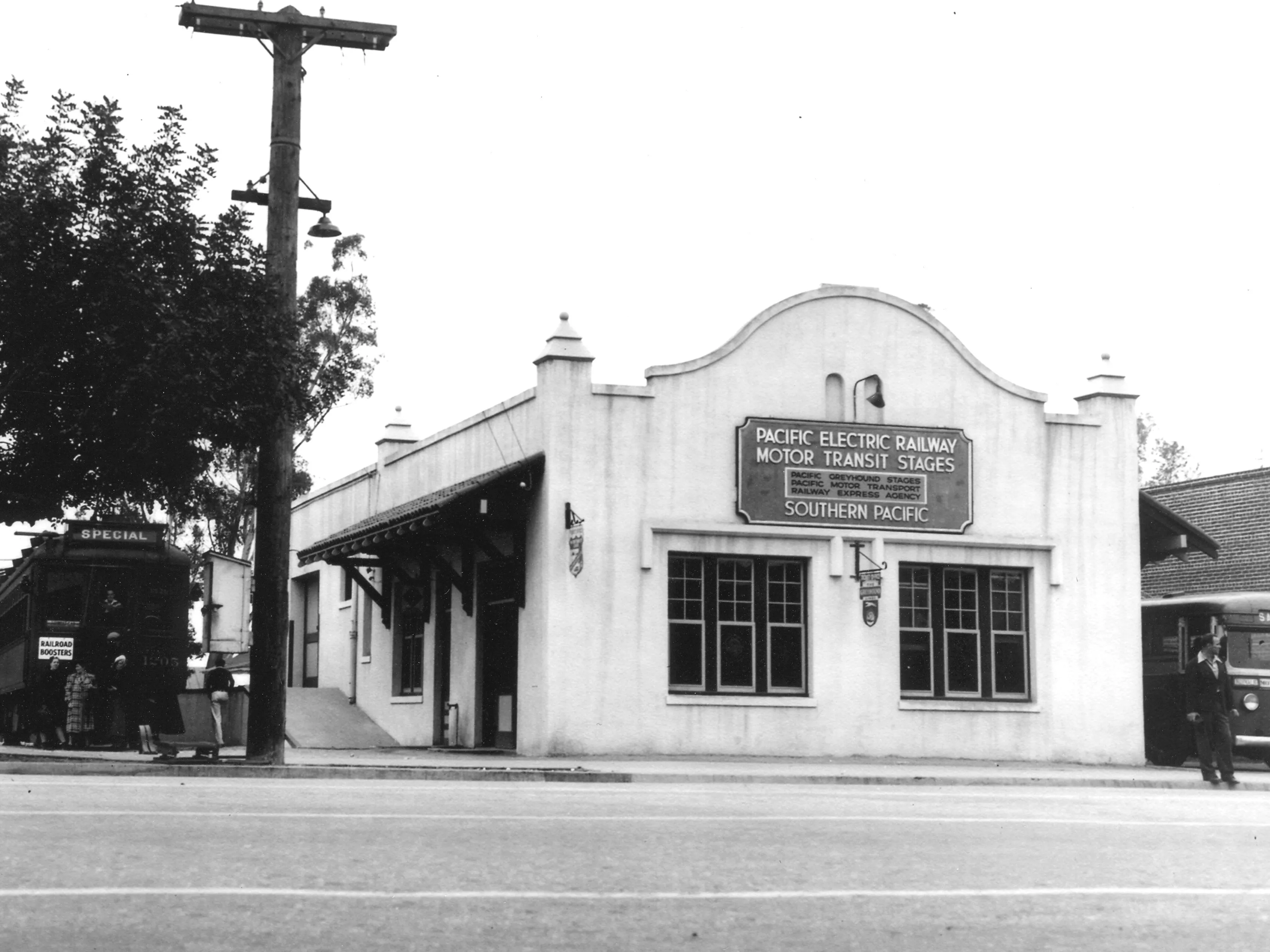 A black and white photograph of the Pacific Electric Depot with waiting Pacific Electric car and bus.