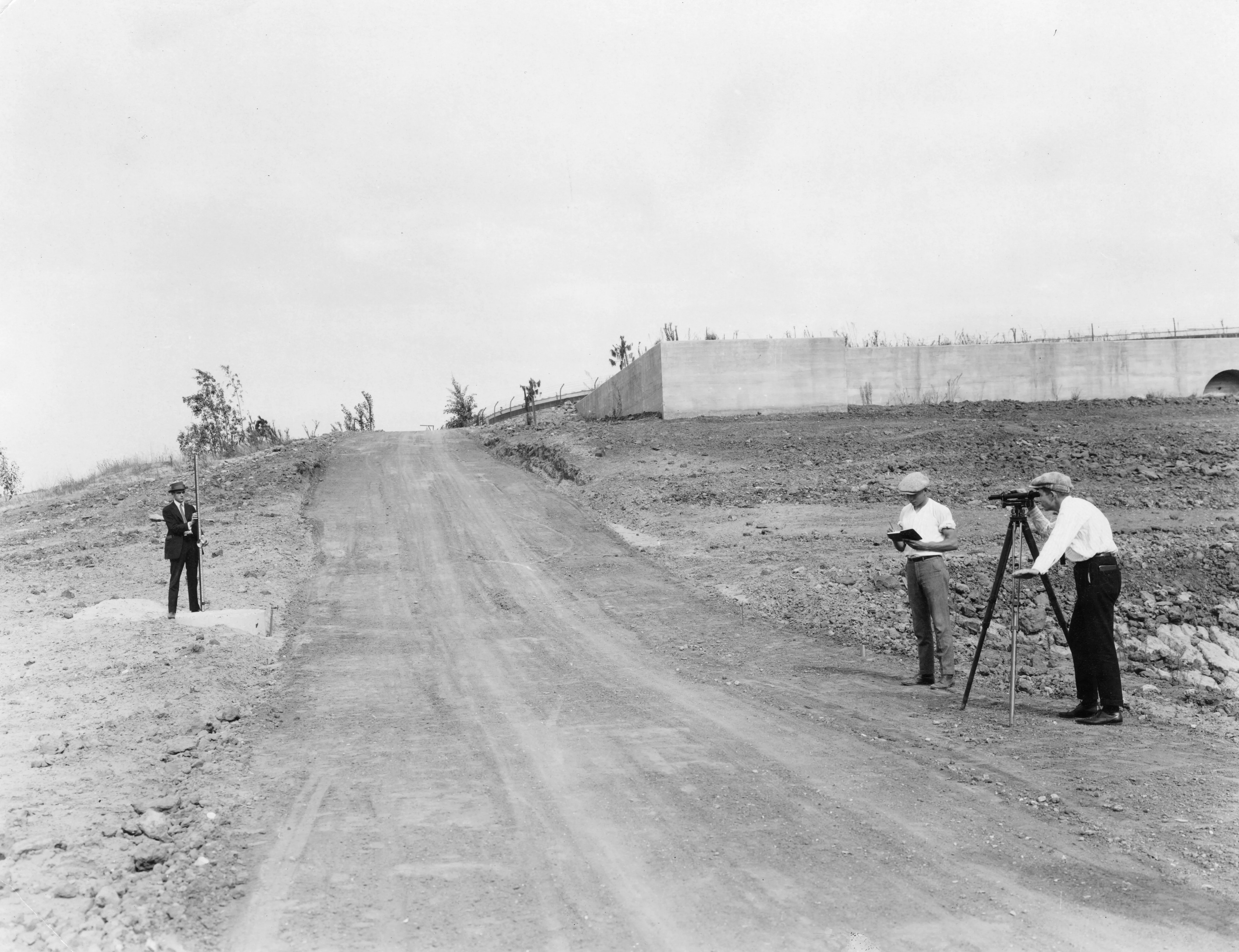 A black and white photograph of three Fullerton College students surveying the Hillcrest Park site.