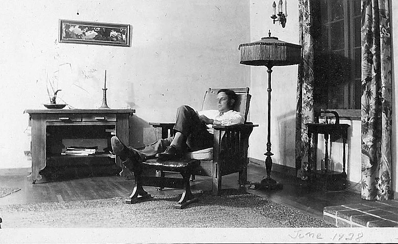 A black and white photograph of Raymond Starbuck asleep on his chair in the living room of the Starbuck House. The photograph is dated June 1928.
