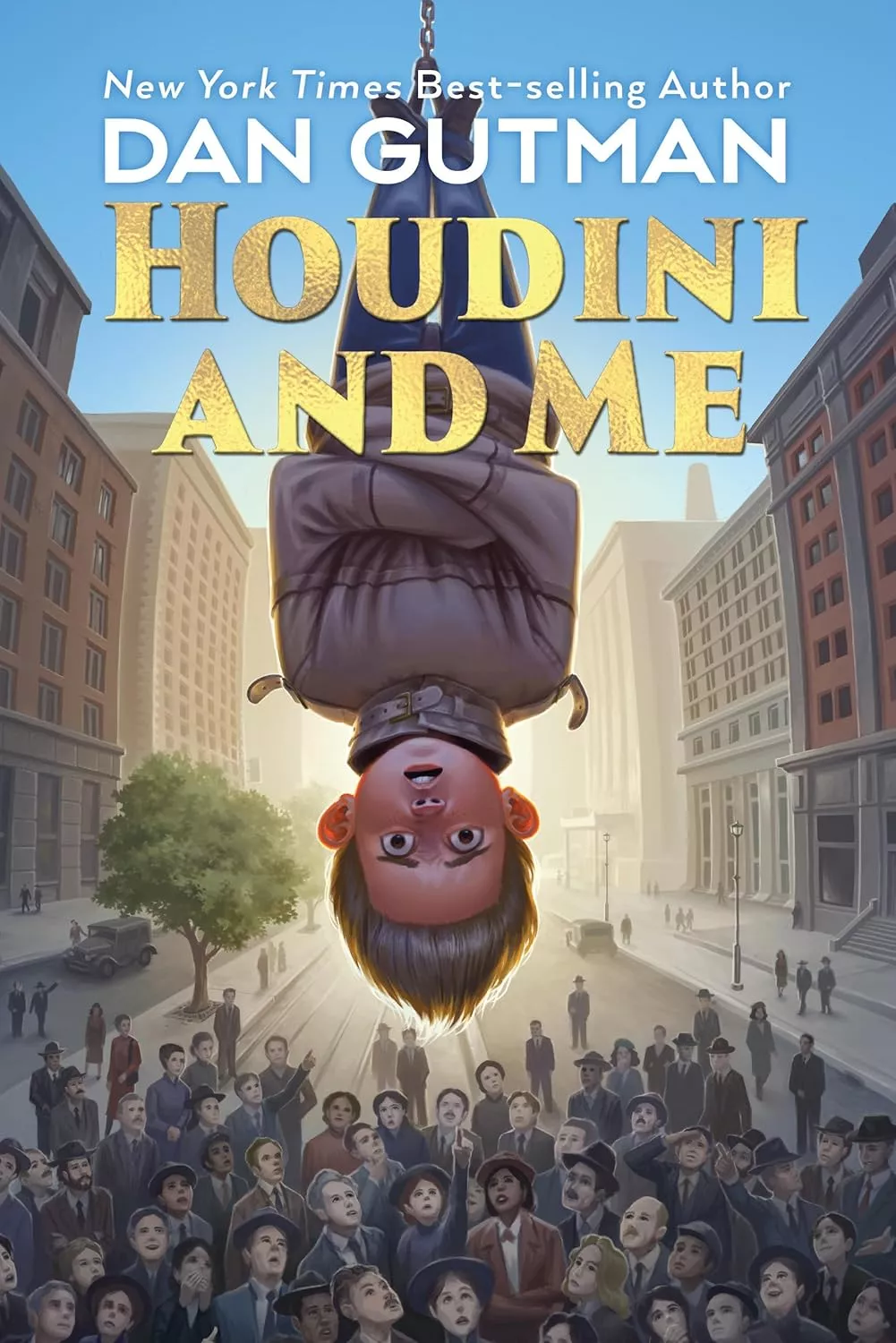 Cover of  Houdini and Me by Dan Gutman depicting a boy wearing a straight jacket, hanging upside down in front of a crowd of onlookers. 